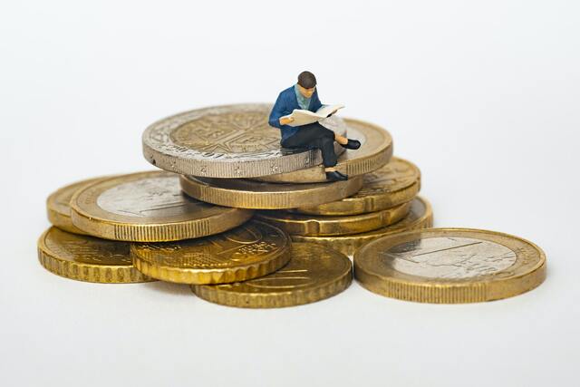 Person reading on top of a pile of coins